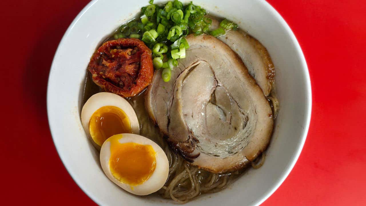 Bowl with slices of chicken, egg and tomatoes with broth. 