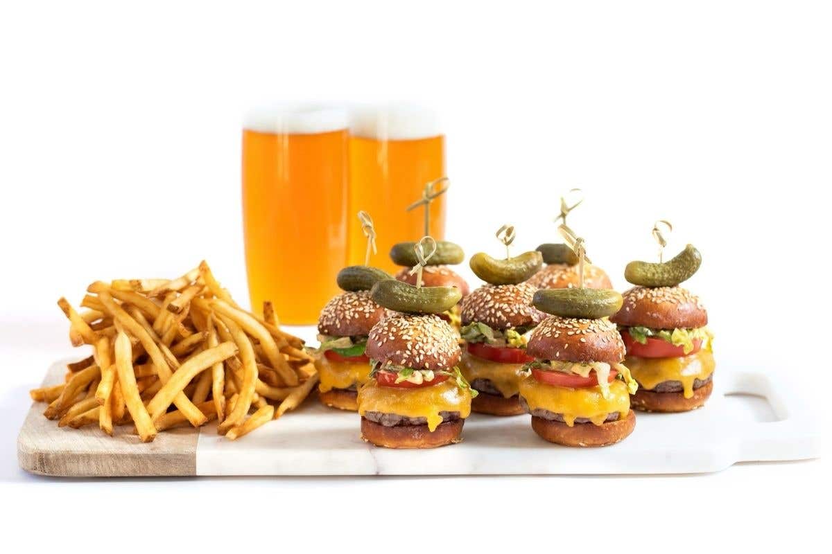 Sandwich sliders, fries and two glasses of beers on a platter. 