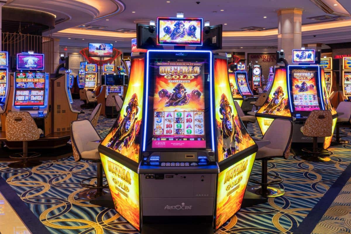Brightly lit casino floor with a row of illuminated slot machines, including a central game featuring a gold-themed design.