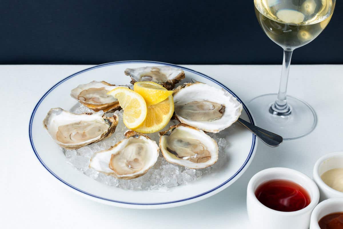 Oysters on a plate with a glass of white wine and sauces.  