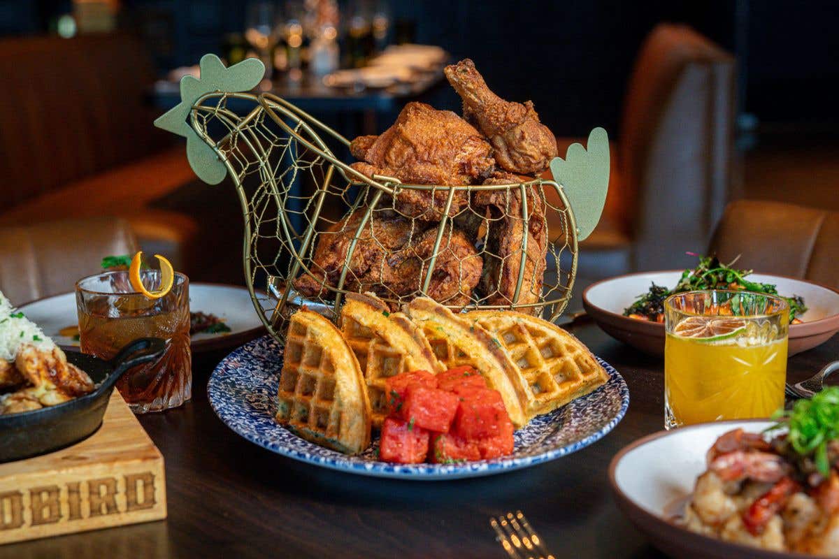 Fried chicken served in a wire basket with waffles and watermelon.