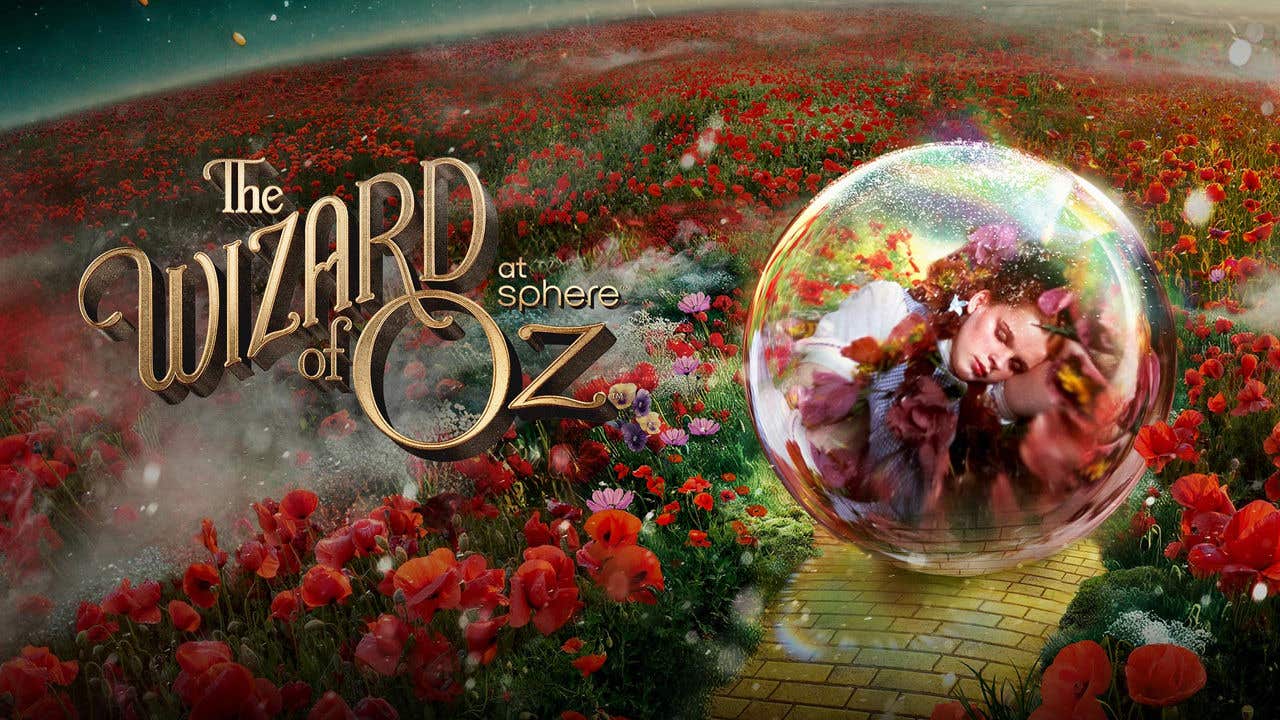 A vast field with red flowers and a yellow brick road with an transparent orb containing a visual of a girl in it, with the text The Wizard of Oz at Sphere to the left