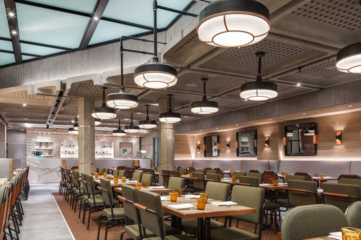 Modern restaurant interior with stylish lighting, tables and chairs neatly arranged, and a contemporary ceiling design.